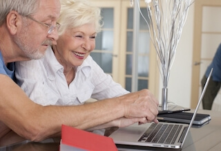 楽しそうにパソコンを操作する老夫婦